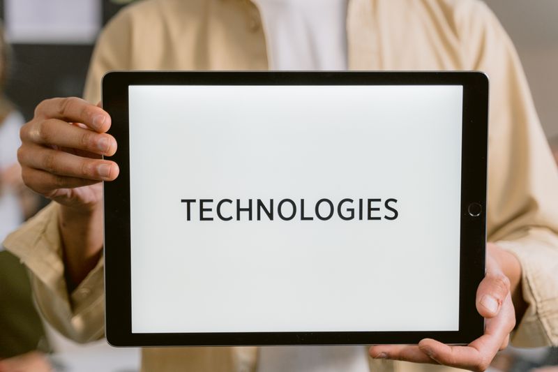 Close-up of a person holding a tablet with the word &lsquo;Technologies&rsquo; on the screen.