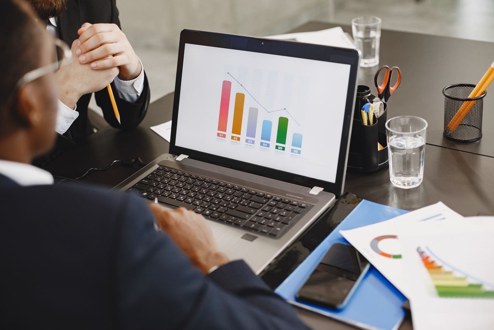 Two professionals analyzing a business graph on a laptop during a meeting.